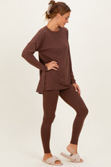 woman wearing a brown long sleeve top and matching leggings, styled with cozy slippers, standing sideways