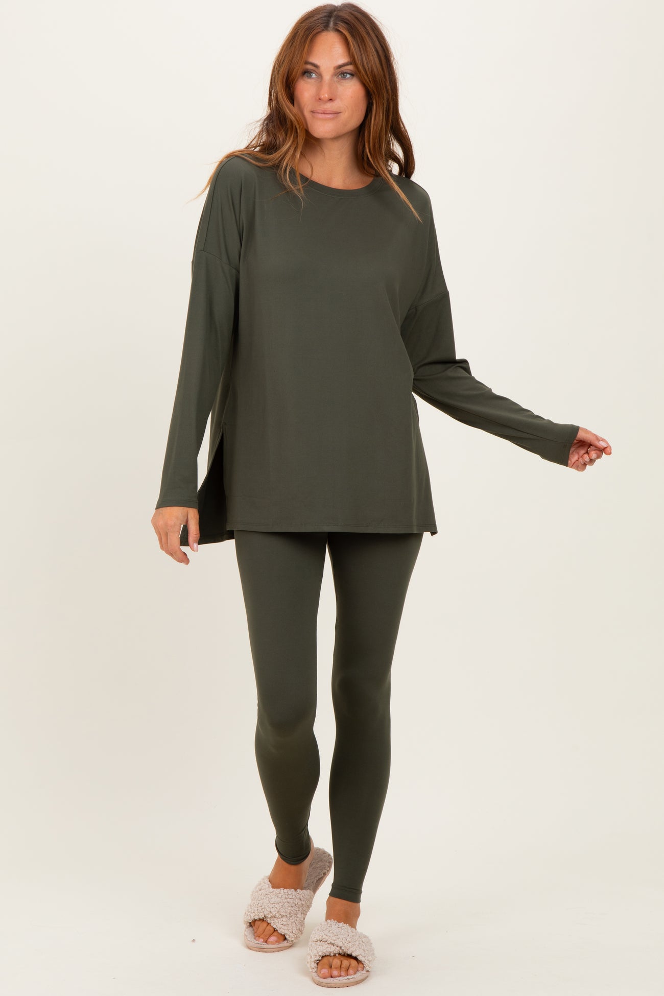 woman wearing an olive green long sleeve top and matching leggings, styled casually with plush slippers