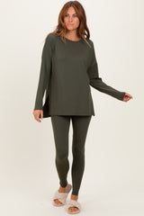 woman wearing an olive green long sleeve top and matching leggings, styled casually with plush slippers