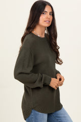 woman wearing a dark green textured long sleeve sweater paired with light blue jeans