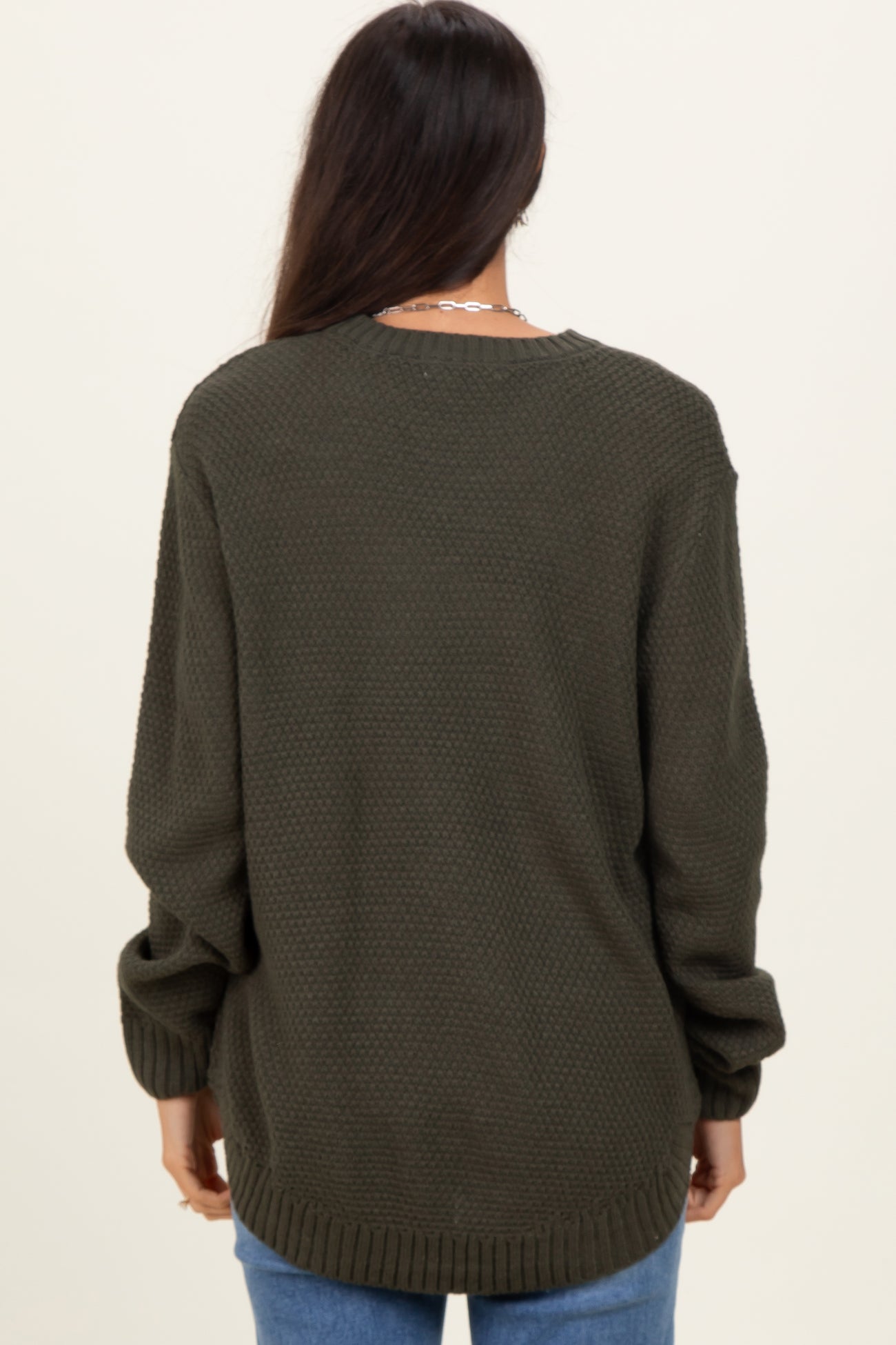 woman wearing an oversized olive green textured sweater with long sleeves and a relaxed fit