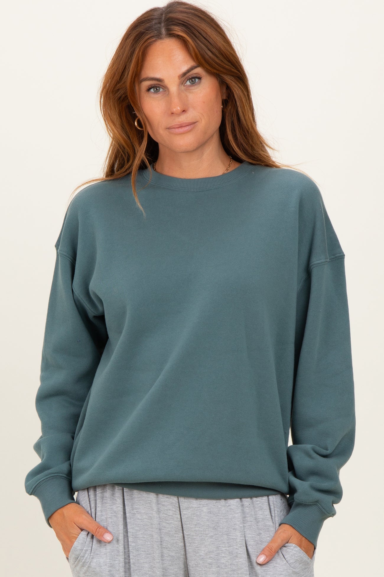 woman wearing a teal oversized sweatshirt with long sleeves and a relaxed fit