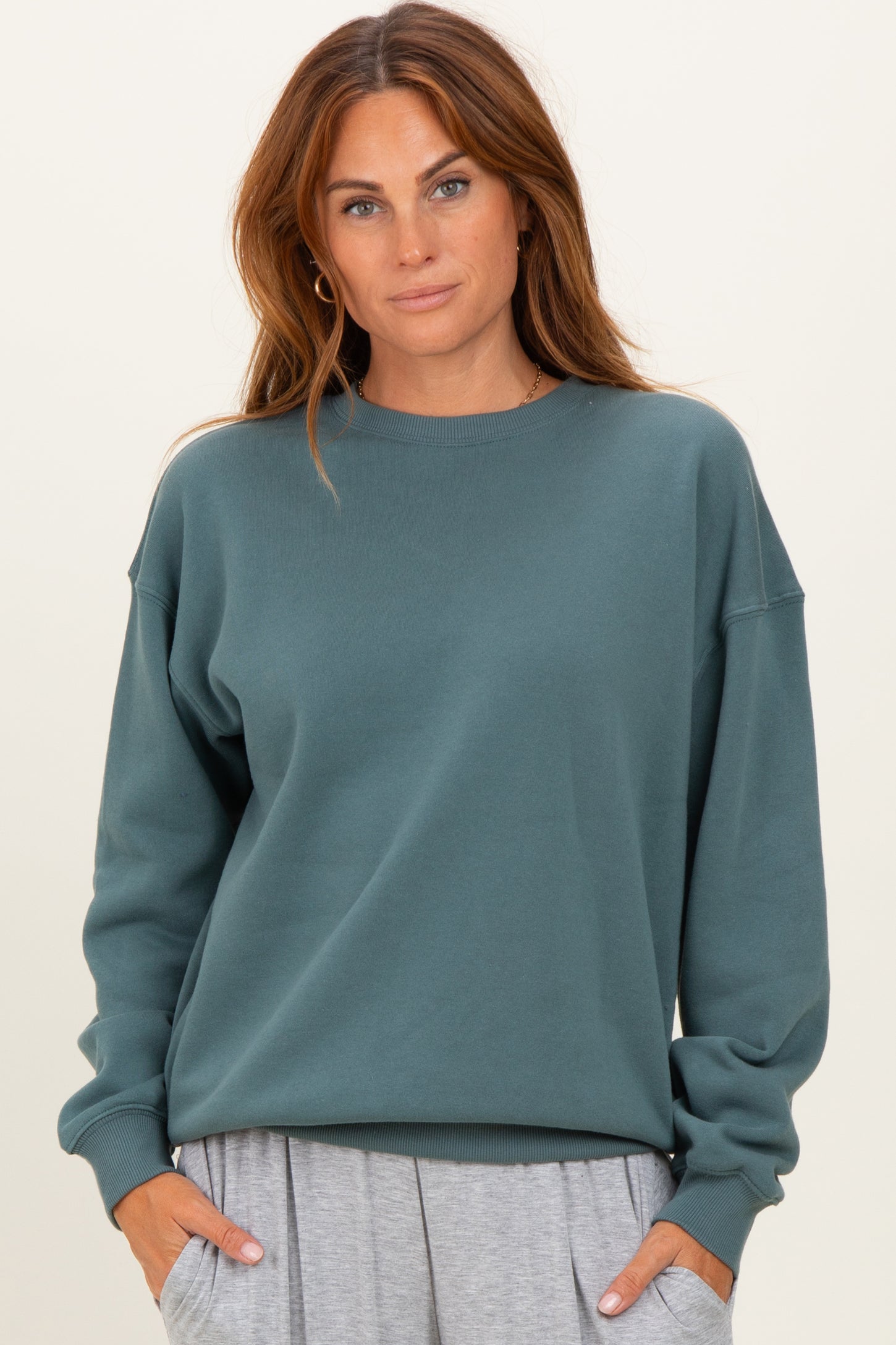 woman wearing a teal oversized sweatshirt with long sleeves and a relaxed fit