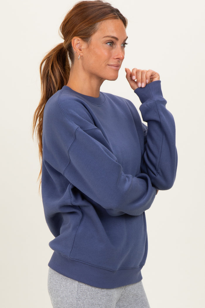 woman wearing a navy blue oversized sweatshirt with long sleeves and a ribbed hem, styled with gray leggings