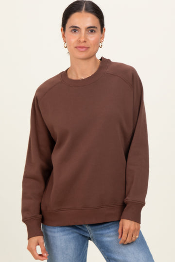 woman wearing a brown oversized sweatshirt with raglan sleeves and a relaxed fit paired with light blue jeans