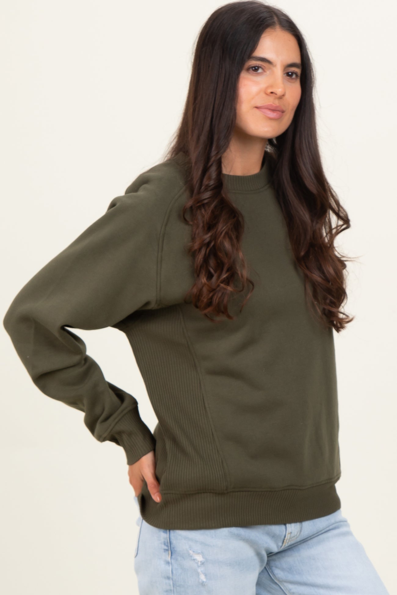 woman wearing an olive green oversized sweatshirt with ribbed details and relaxed fit