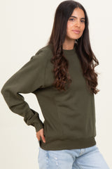 woman wearing an olive green oversized sweatshirt with ribbed details and relaxed fit