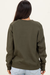woman wearing a dark green long sleeve sweatshirt seen from the back with a relaxed fit and ribbed hem