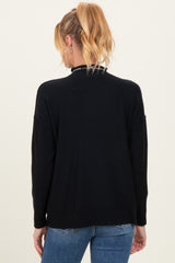 woman wearing a black maternity sweater with a relaxed fit and rolled sleeves, showing the back view