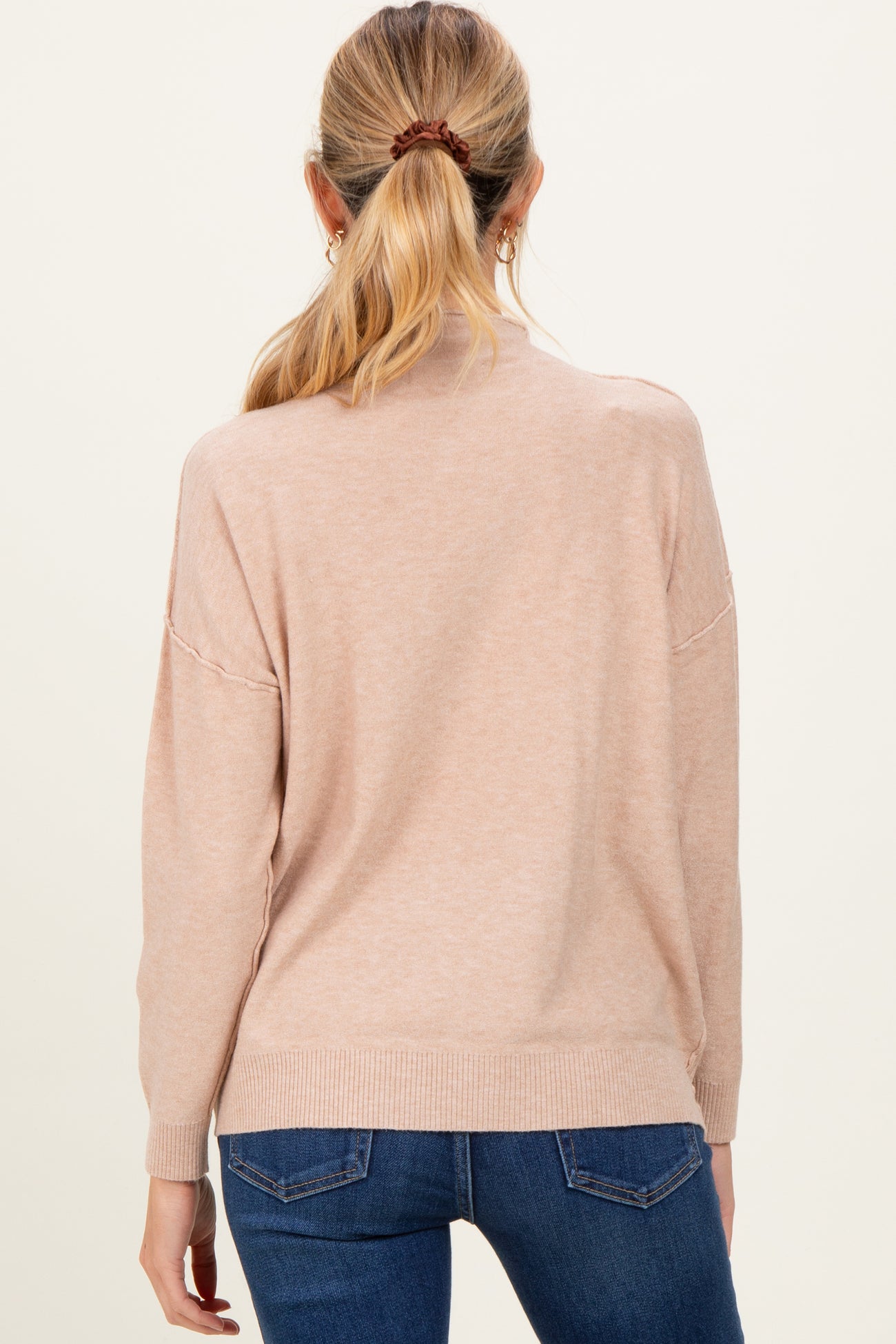 woman wearing a light pink maternity sweater with a relaxed fit and long sleeves, shown from the back