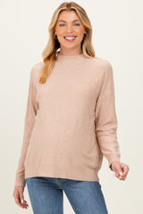 woman wearing a blush pink maternity sweater with a high neckline and relaxed fit, showcasing her baby bump