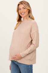 woman wearing a light brown maternity sweater with a relaxed fit and holding her baby bump