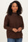 woman wearing a dark brown long sleeve sweater with a high neckline and relaxed fit, styled with light blue jeans