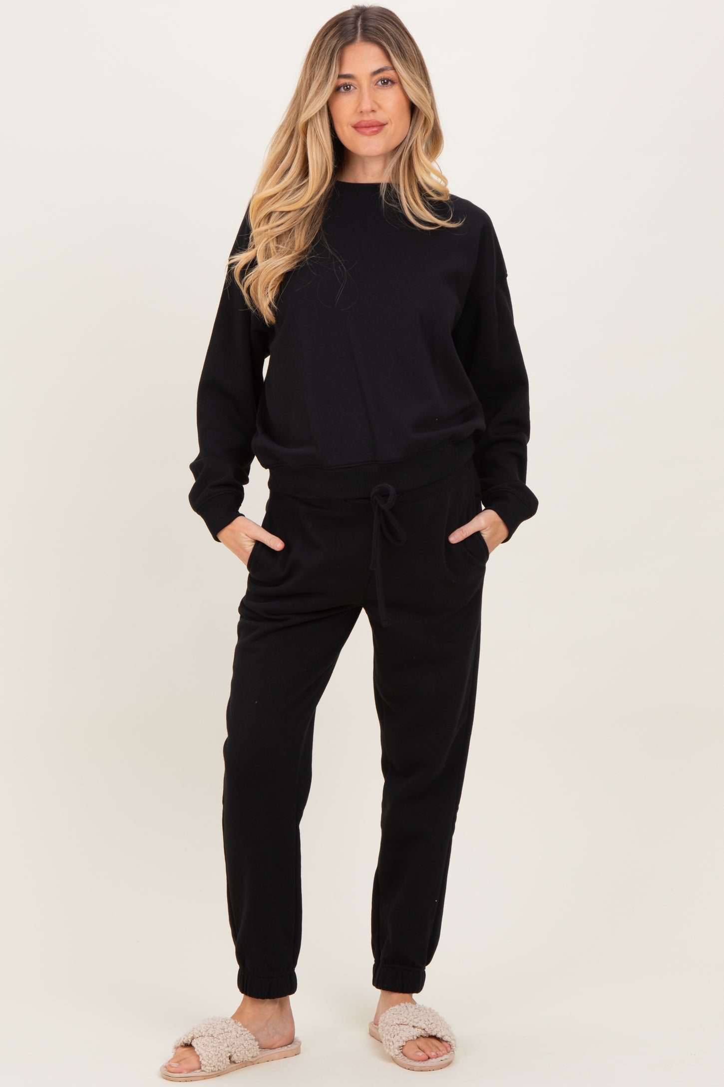 woman wearing a black maternity loungewear set with a relaxed fit sweatshirt and jogger pants, enjoying comfort at home