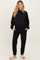 woman wearing a black maternity loungewear set with a relaxed fit sweatshirt and jogger pants, enjoying comfort at home
