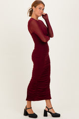 woman wearing a burgundy long sleeve fitted dress with ruching details and a bodycon silhouette
