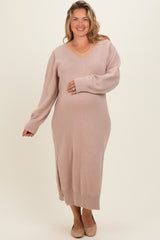 woman wearing a light pink maternity plus sweater dress with a v-neck and side slit, holding her baby bump