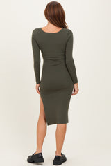 woman wearing a dark green ribbed midi dress with long sleeves and a side slit