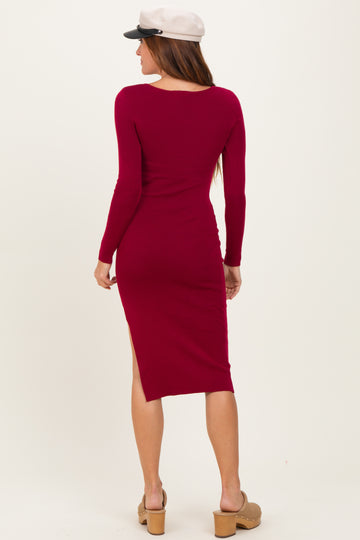 woman wearing a burgundy ribbed midi dress with long sleeves and a side slit, seen from the back