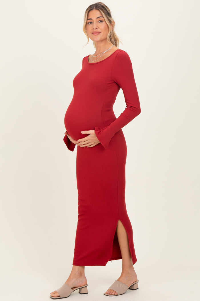 woman wearing a red ribbed maternity dress with side slits and holding her baby bump