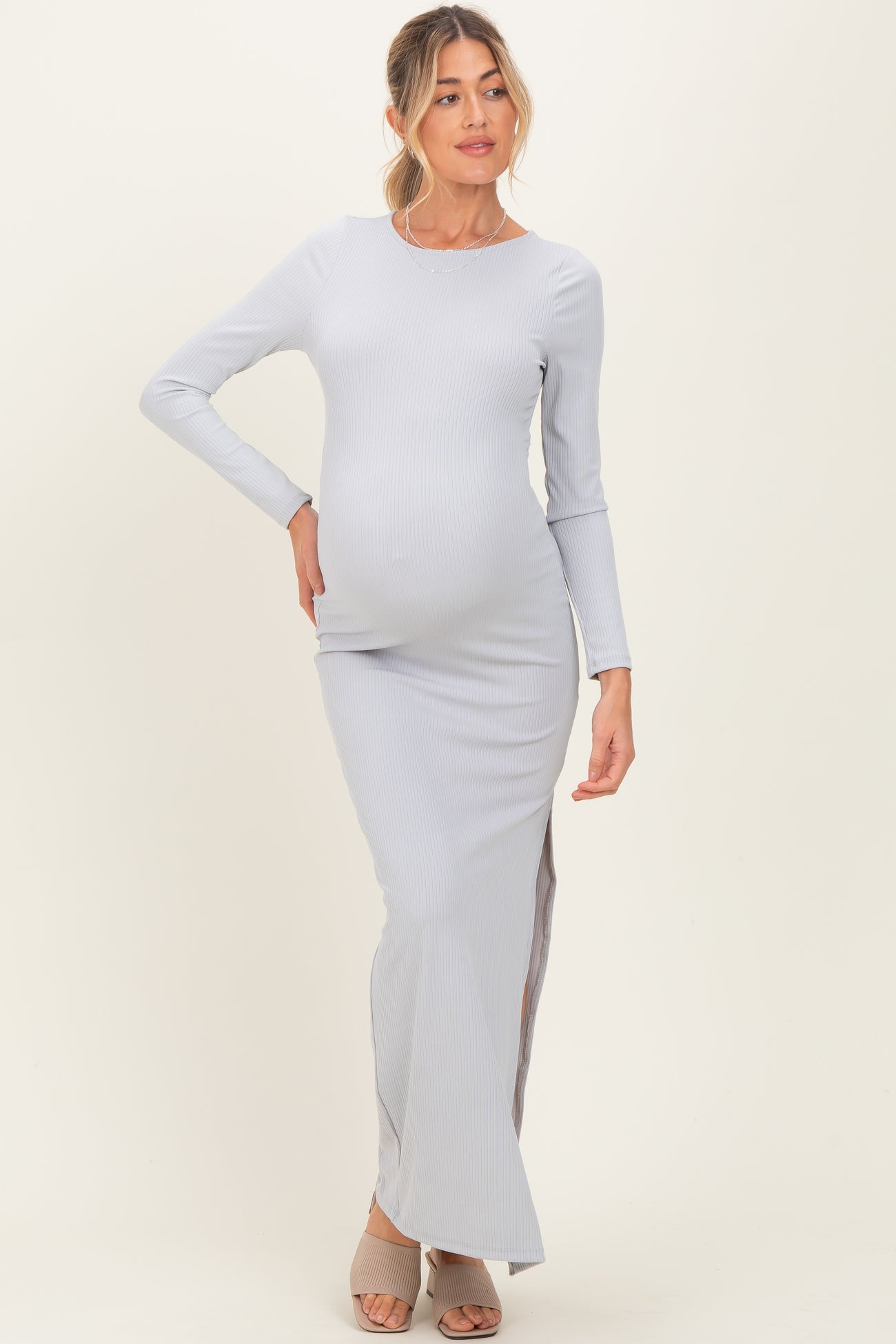 woman wearing a light grey ribbed maternity maxi dress with side slits and a visible baby bump