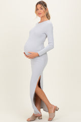 woman wearing a light gray ribbed maternity maxi dress with side slits and holding her baby bump