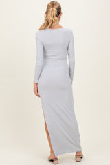 woman wearing a light gray long sleeve maternity maxi dress with a side slit and fitted silhouette