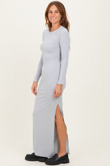 woman wearing a light gray long sleeve ribbed maxi dress with a side slit and black platform shoes