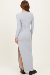 woman wearing a light gray long sleeve ribbed maxi dress with a side slit, shown from the back