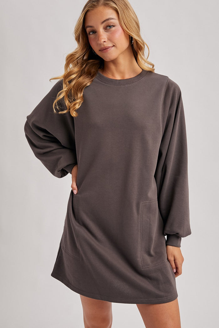 woman wearing a dark gray oversized sweatshirt dress with long sleeves and side pockets