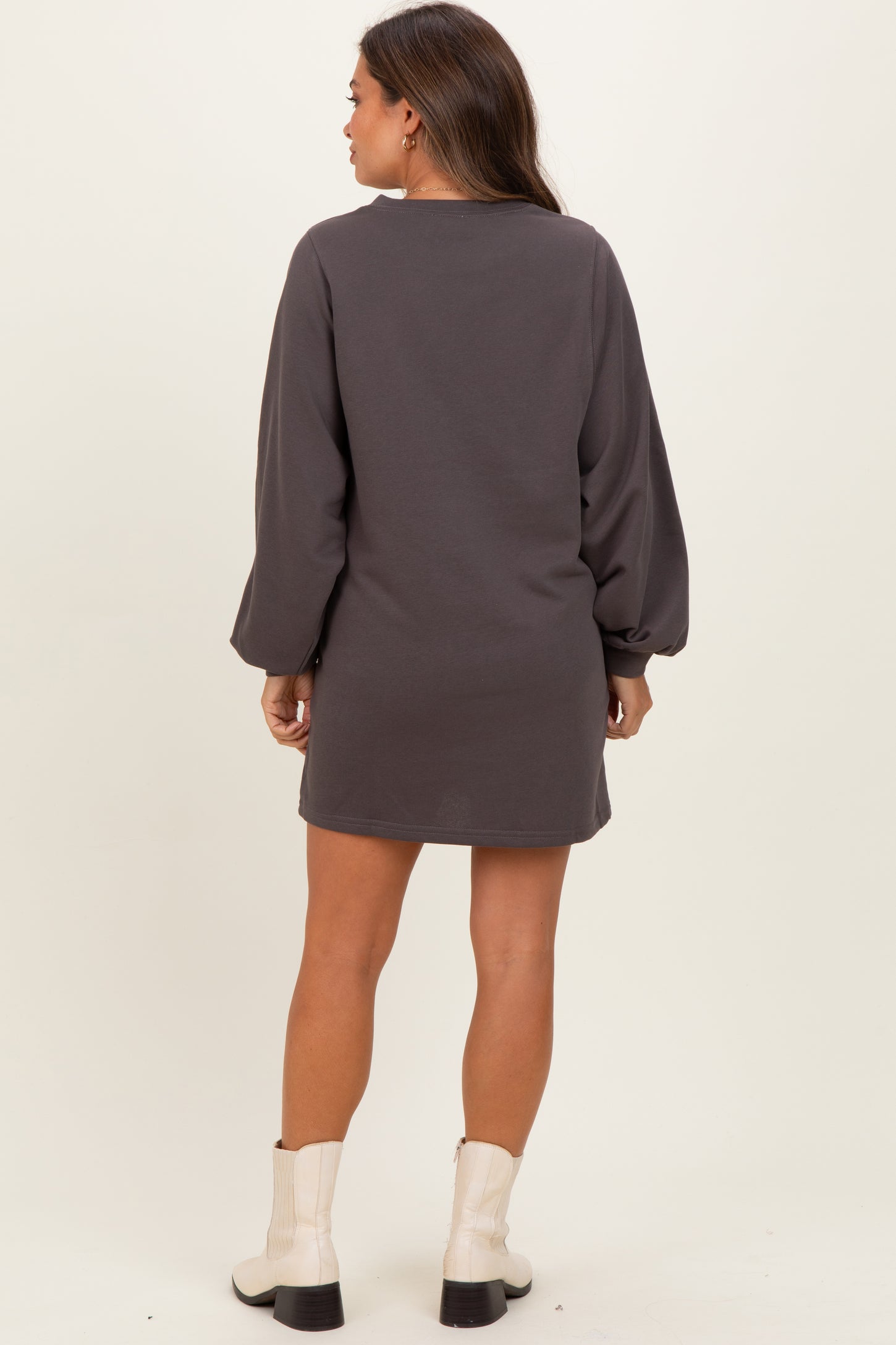 woman wearing a dark gray maternity dress with long sleeves and a relaxed fit, styled with ankle boots