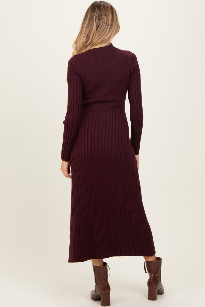 woman wearing a burgundy ribbed maternity dress with long sleeves and a fitted silhouette, showing a pregnant belly