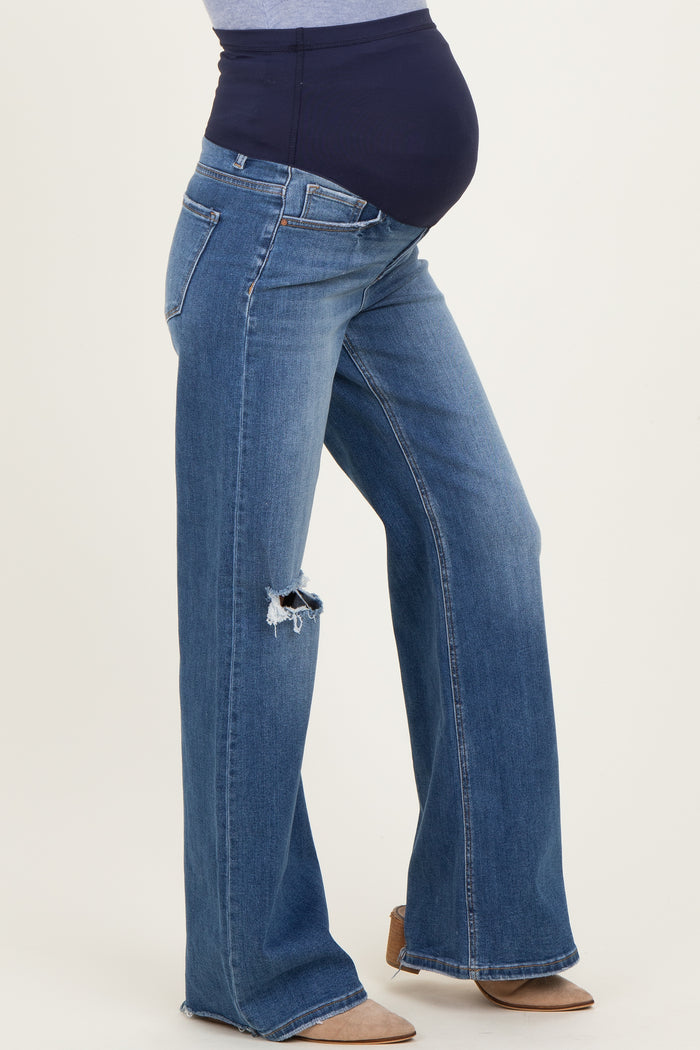 maternity wear blue distressed flare jeans with a black over-the-bump panel and visible baby bump