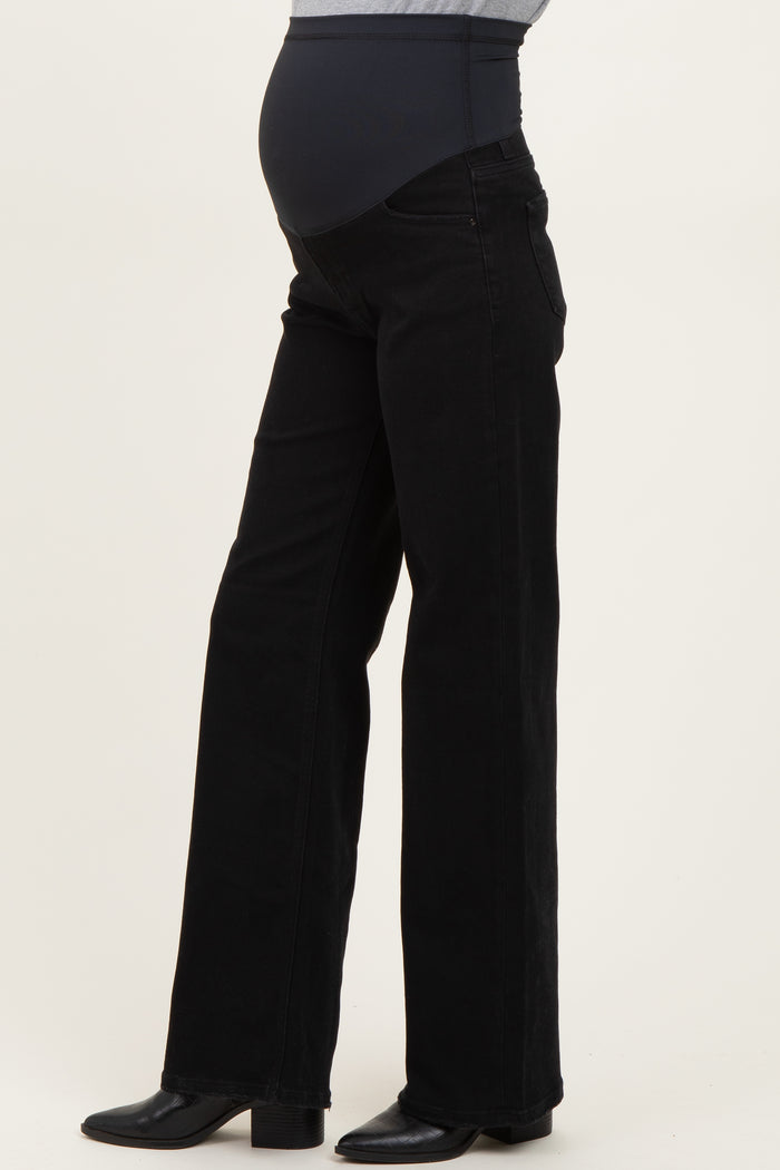 woman wearing black maternity flare jeans with a high waistband and a visible baby bump