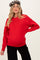woman wearing a red oversized knit maternity sweater with a visible baby bump and a leopard print beret