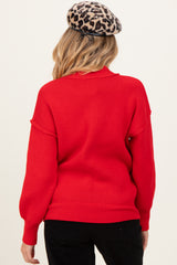 woman wearing a red maternity sweater with a loose fit and a high neckline, viewed from the back