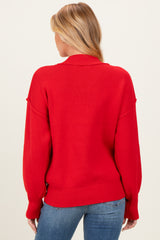 woman wearing a red oversized maternity sweater from the back, with relaxed fit and ribbed detailing