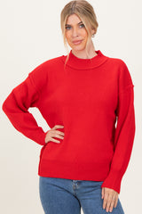 woman wearing a bright red ribbed knit sweater with a mock neck and long sleeves, styled with blue jeans