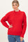 woman wearing a bright red ribbed knit sweater with a mock neck and long sleeves, styled with blue jeans