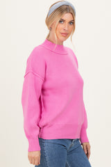 woman wearing a hot pink ribbed sweater with a mock neck and balloon sleeves, paired with blue jeans