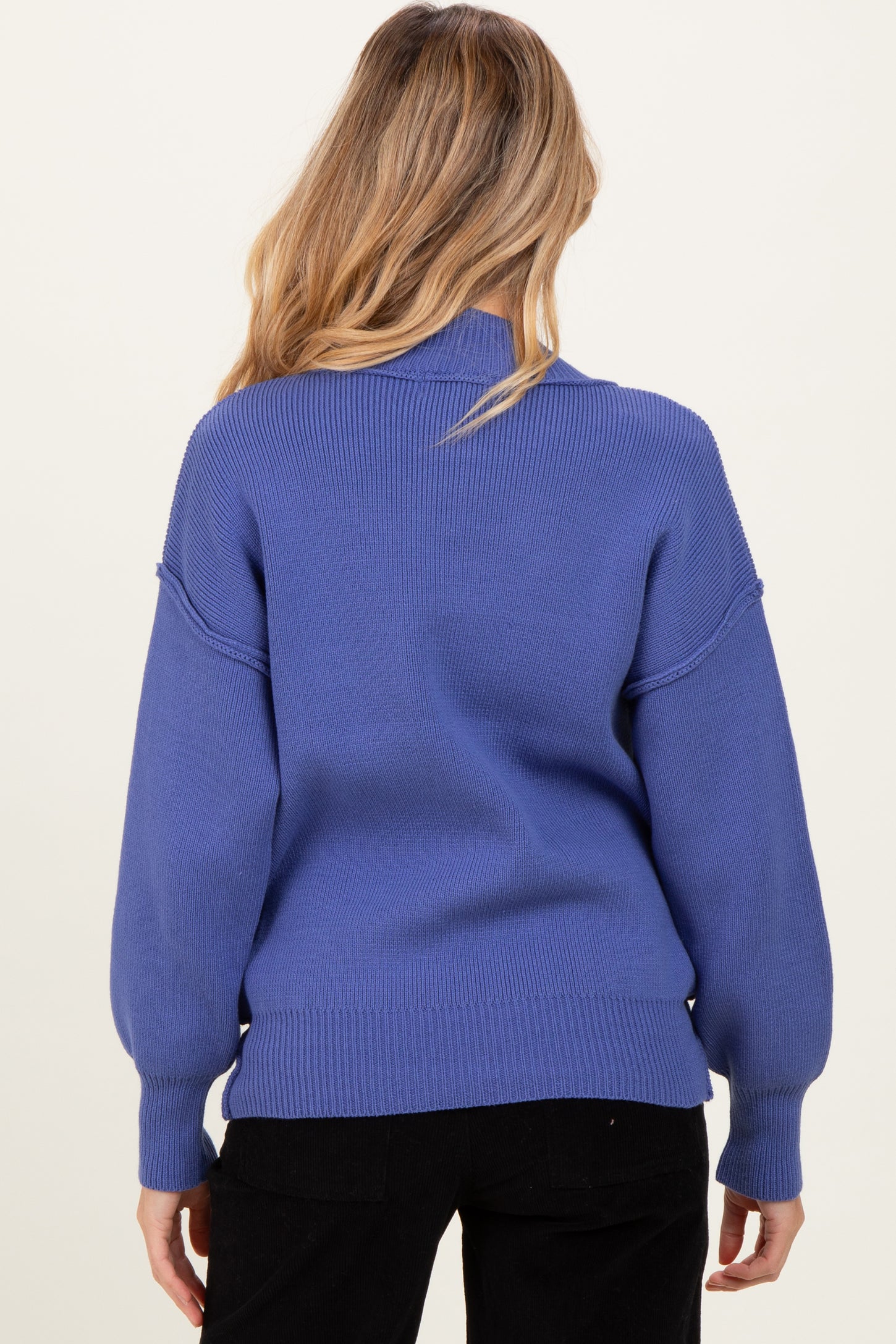 woman wearing a blue long sleeve maternity sweater with a relaxed fit, shown from the back