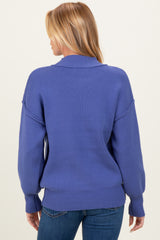 woman wearing a blue oversized maternity sweater with a relaxed fit and dropped shoulders, seen from the back