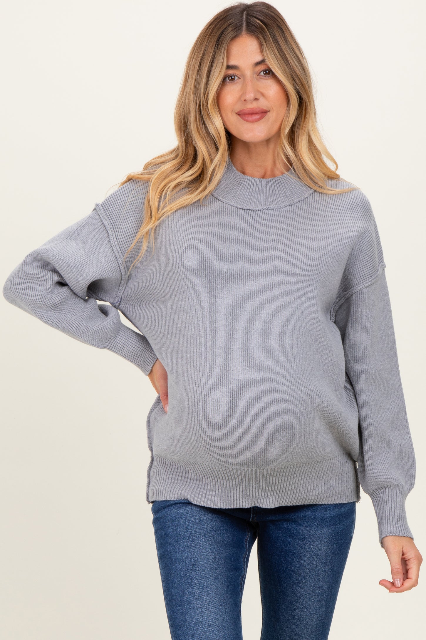 woman wearing a cozy light gray maternity sweater with a relaxed fit and visible baby bump