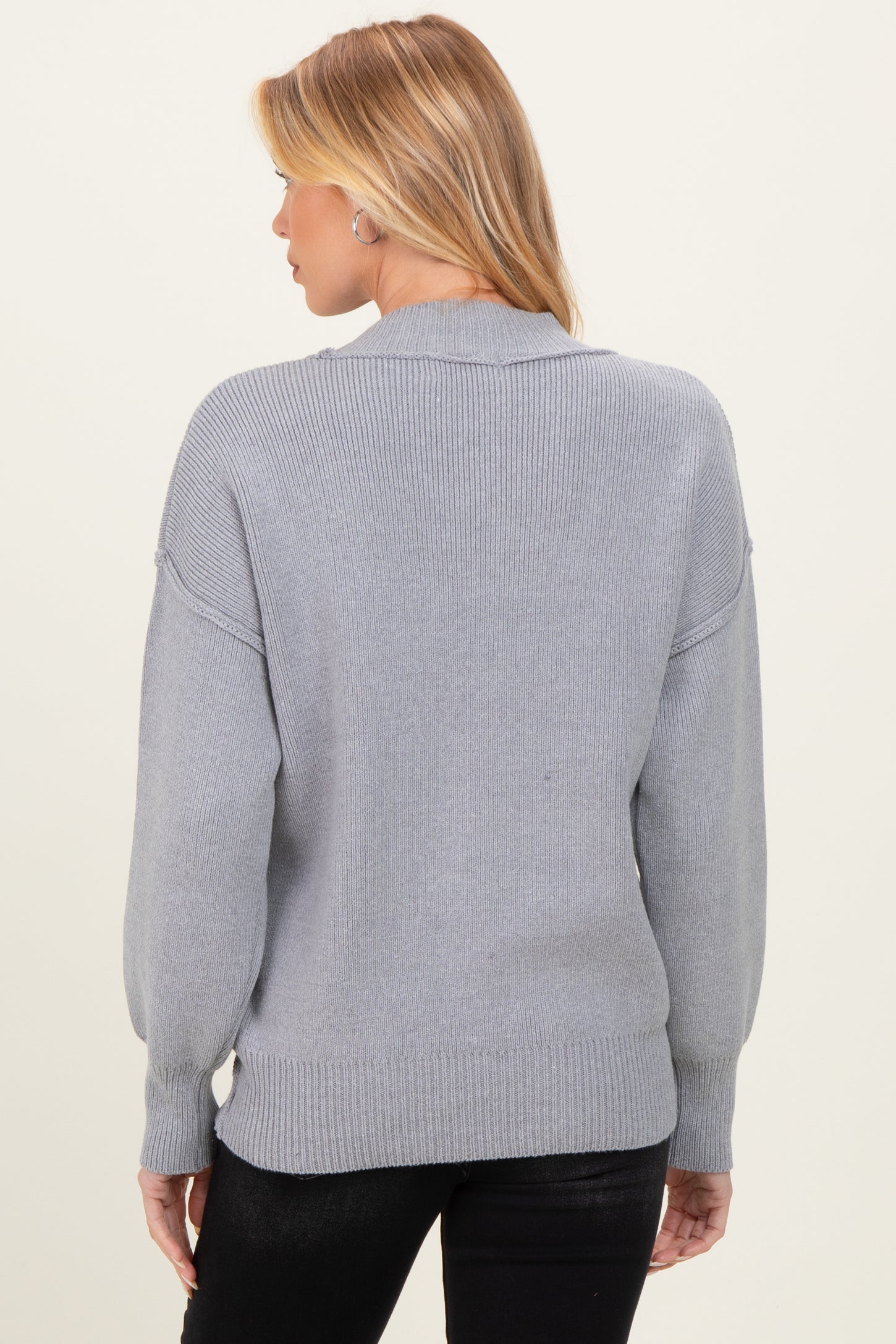 woman wearing a gray maternity sweater with balloon sleeves, seen from the back