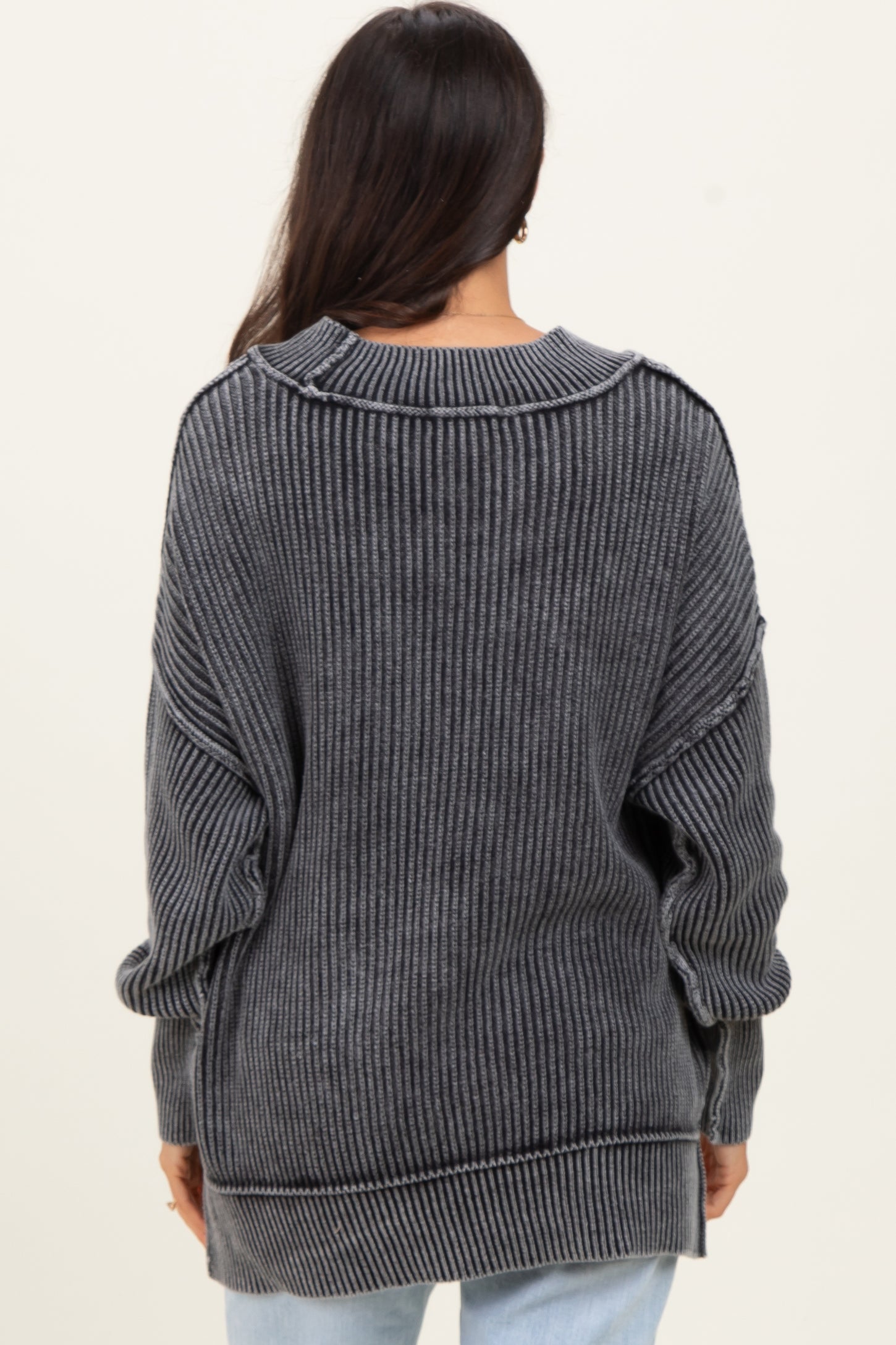woman wearing a dark gray oversized ribbed sweater with long sleeves and a relaxed fit, viewed from the back