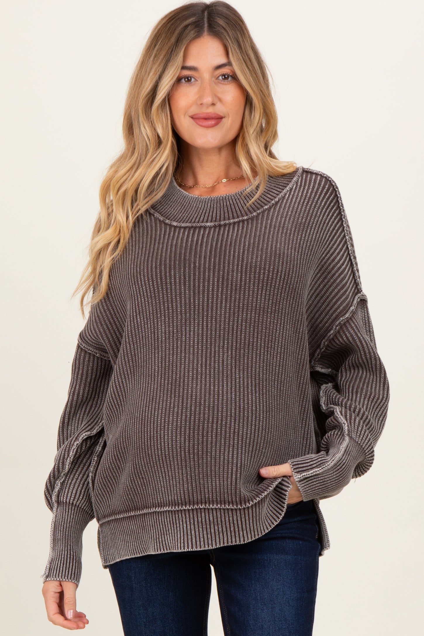 woman wearing a gray ribbed maternity sweater with a relaxed fit and long sleeves, holding her baby bump