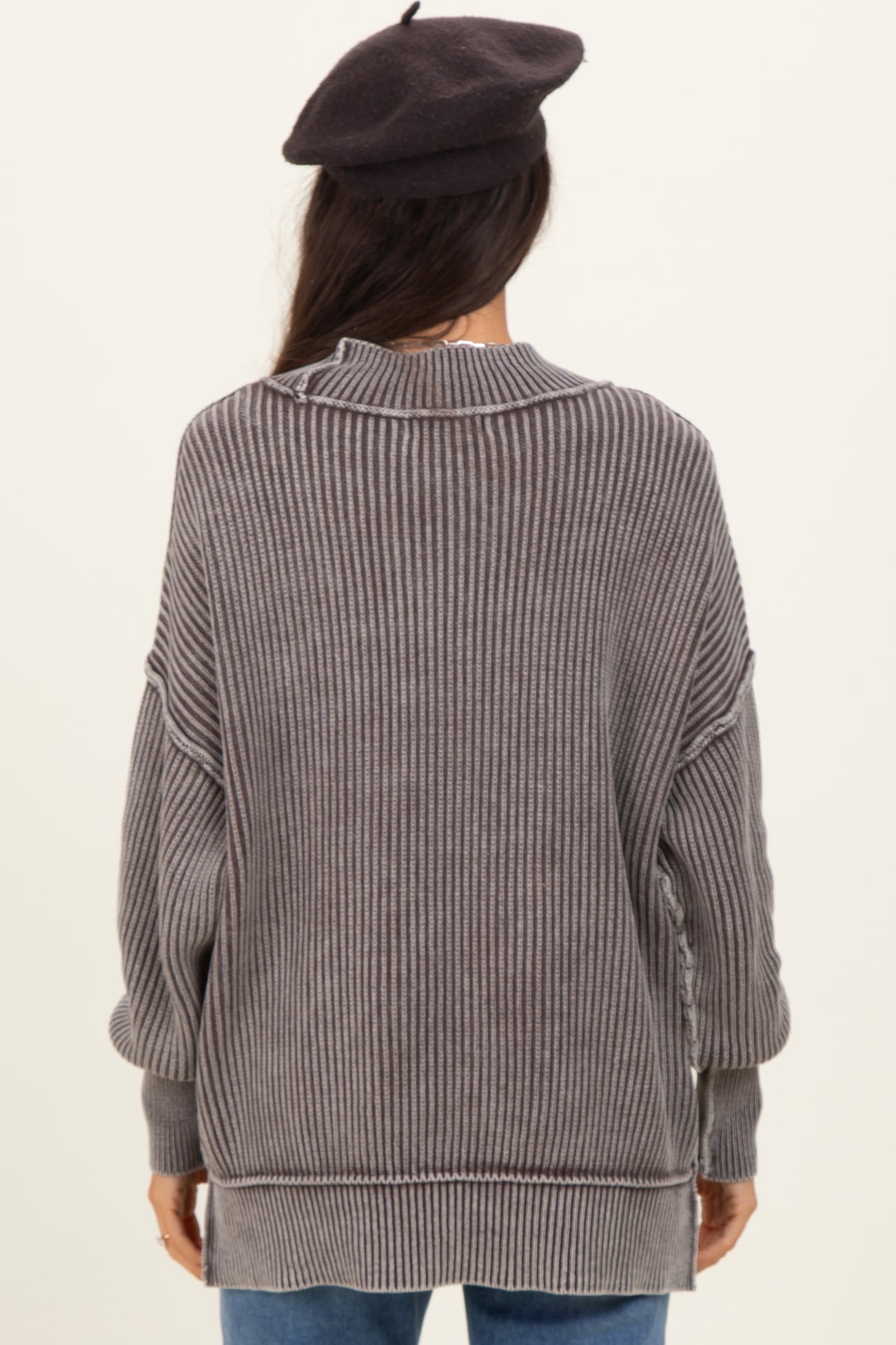 woman wearing a cozy gray striped oversized sweater with a high collar and relaxed fit, viewed from the back
