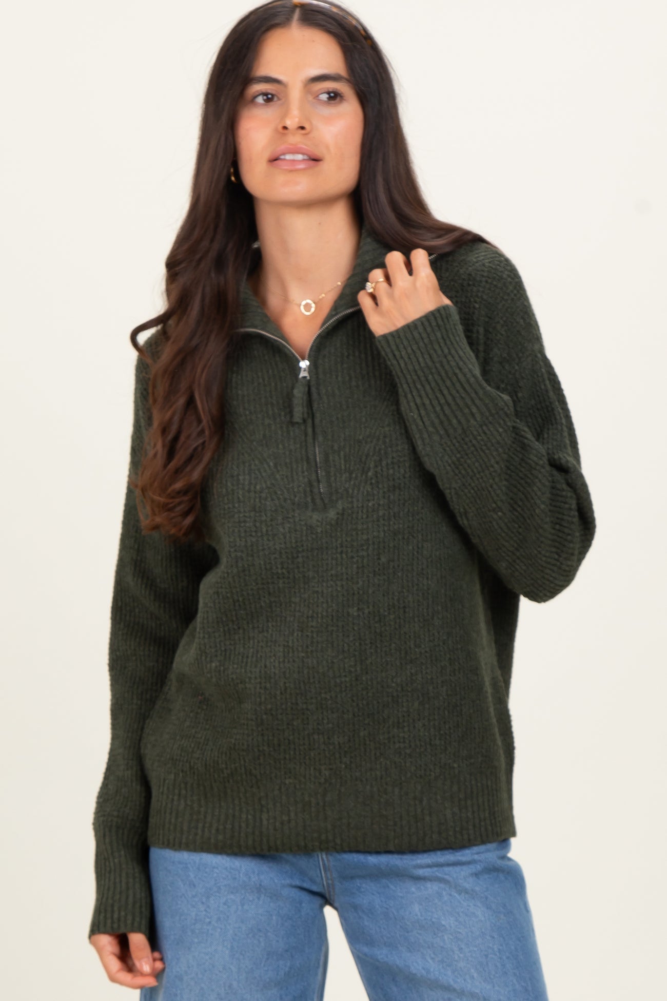 woman wearing a dark green zip-up sweater with a relaxed fit and ribbed details, paired with blue jeans