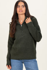 woman wearing a dark green zip-up sweater with a relaxed fit and ribbed details, paired with blue jeans