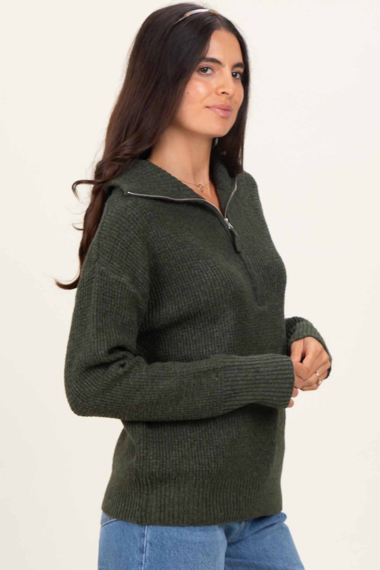 woman wearing a dark green zip-up sweater with ribbed detailing and long sleeves
